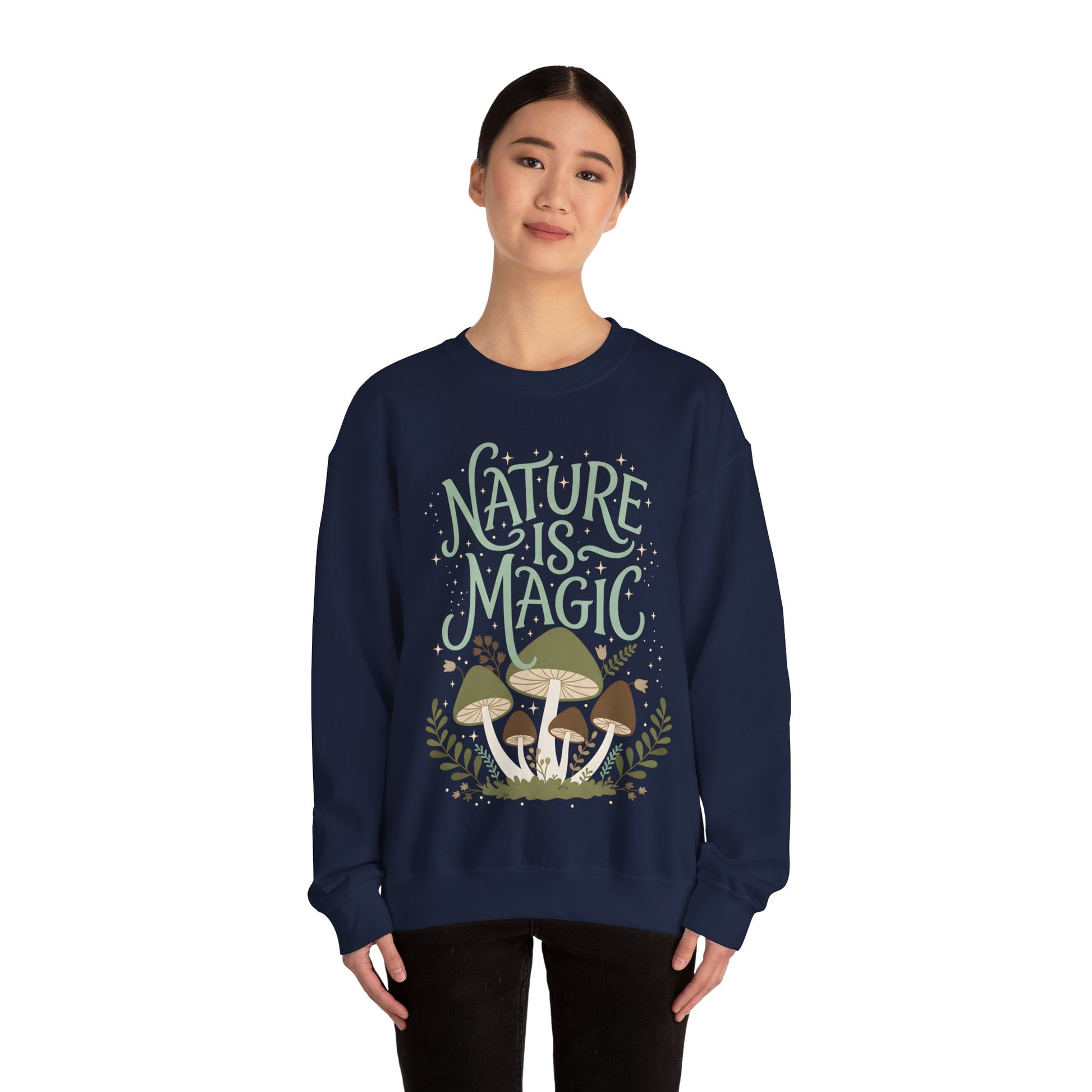 Model wearing a purple nature-themed sweatshirt with “Nature Is Magic” text and whimsical mushrooms and foliage illustration, showing relaxed unisex fit.