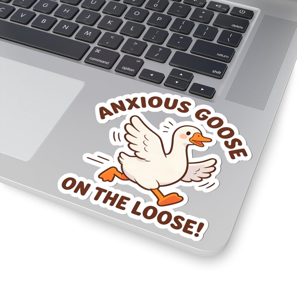 A kiss-cut vinyl sticker featuring a cartoon white goose with orange beak and feet, surrounded by the text 'ANXIOUS GOOSE ON THE LOOSE!' in brown, shown applied to the lower left corner of a silver laptop.