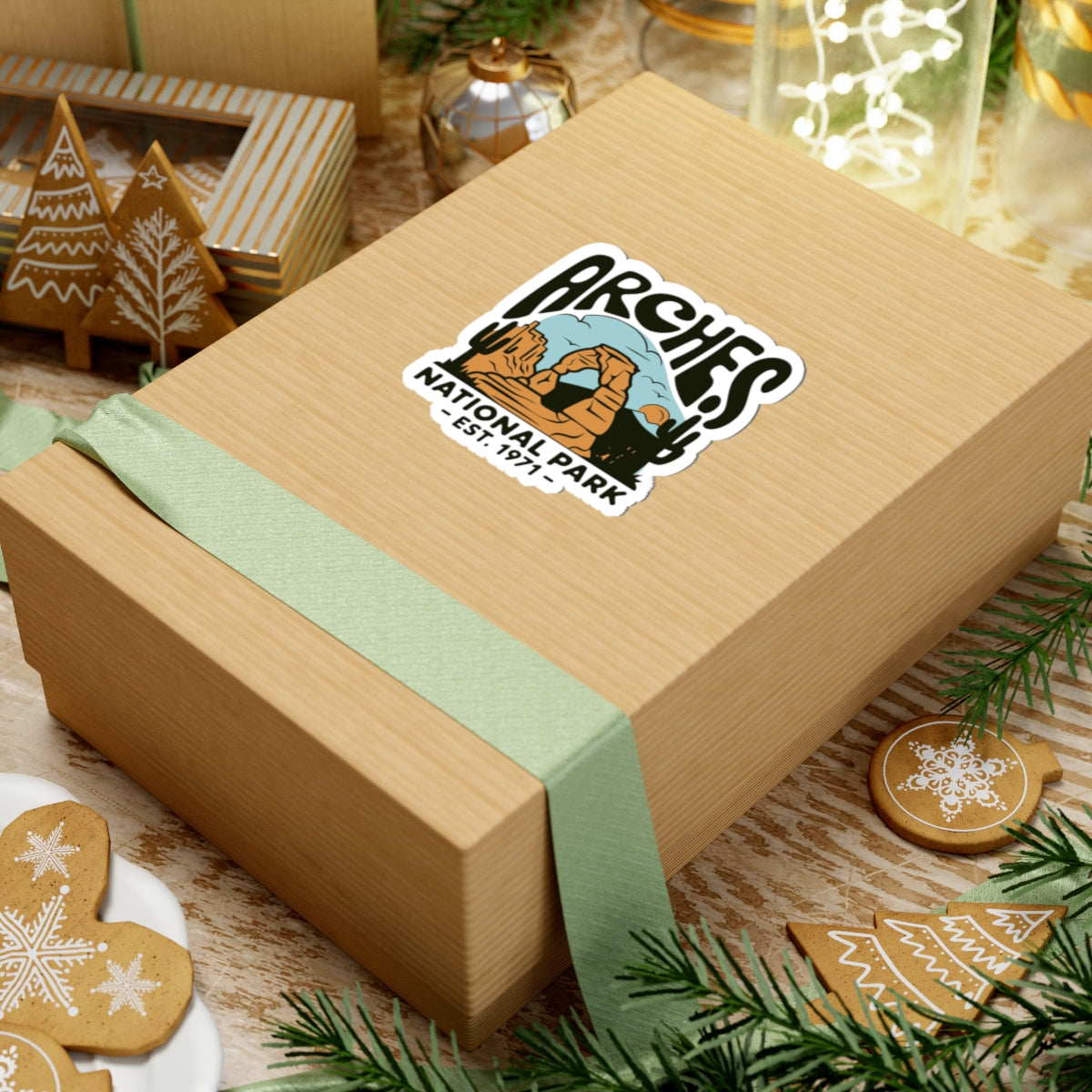 Wooden gift box with a decorative Arches National Park sticker on a festive background with cookies and lights.
