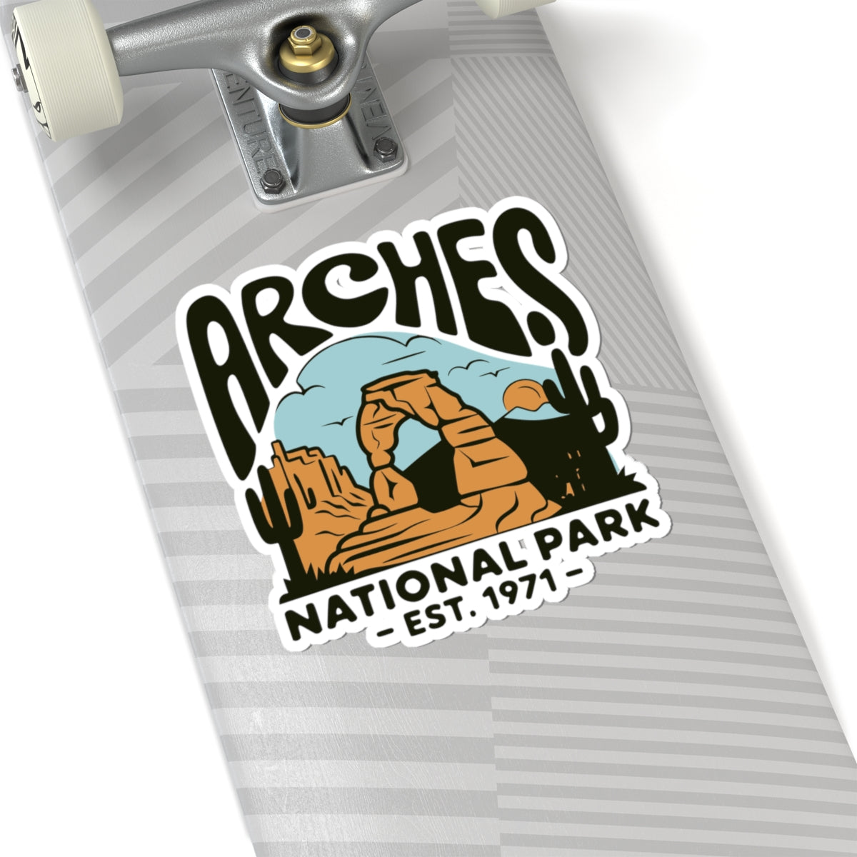 A close-up of a skateboard deck featuring a kiss-cut sticker that reads 'ARCHES NATIONAL PARK - EST. 1971' with a desert arch illustration.