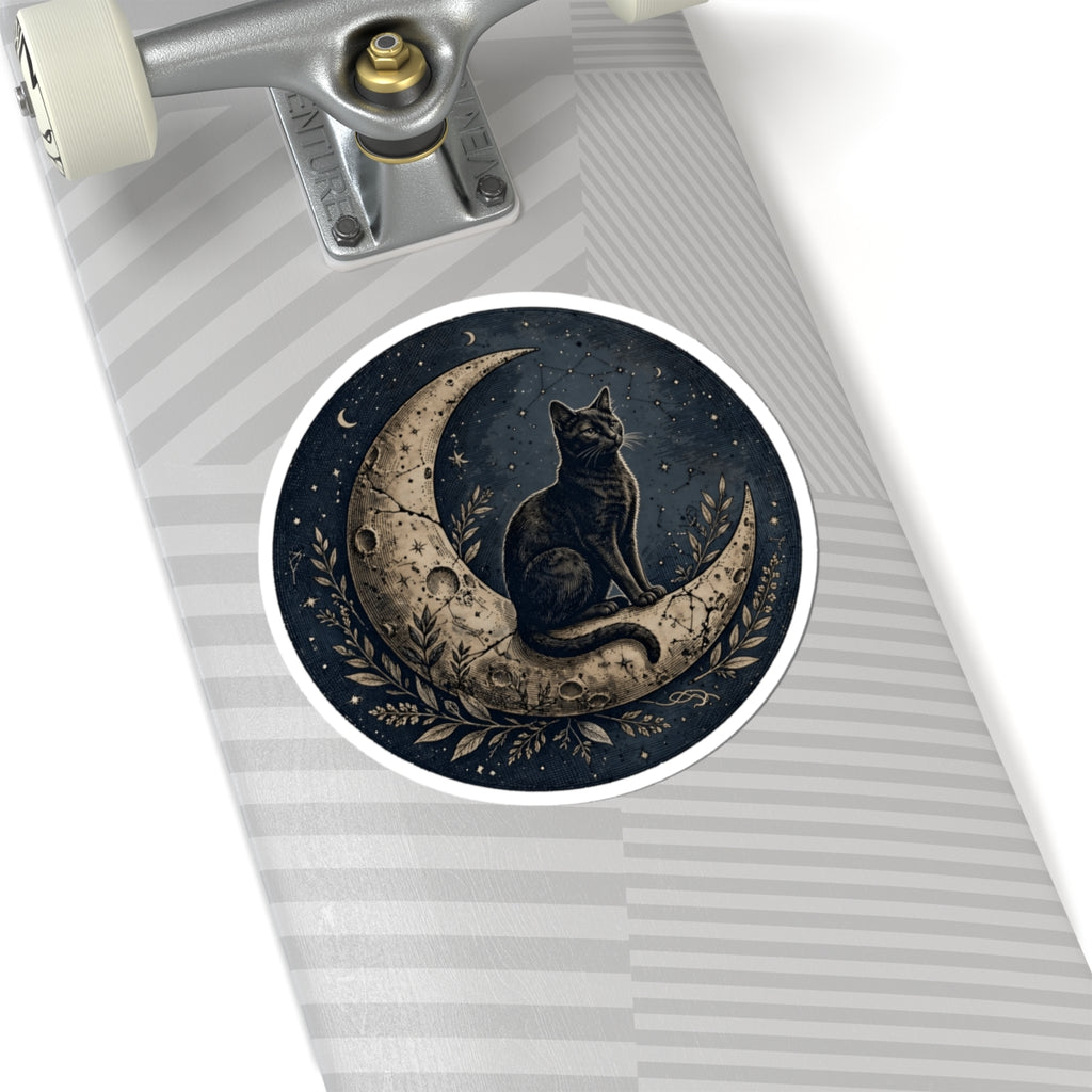 A close-up of a skateboard deck featuring a circular sticker of a black cat sitting on a crescent moon under a starry night sky, with a gray striped deck background and part of the silver truck visible.