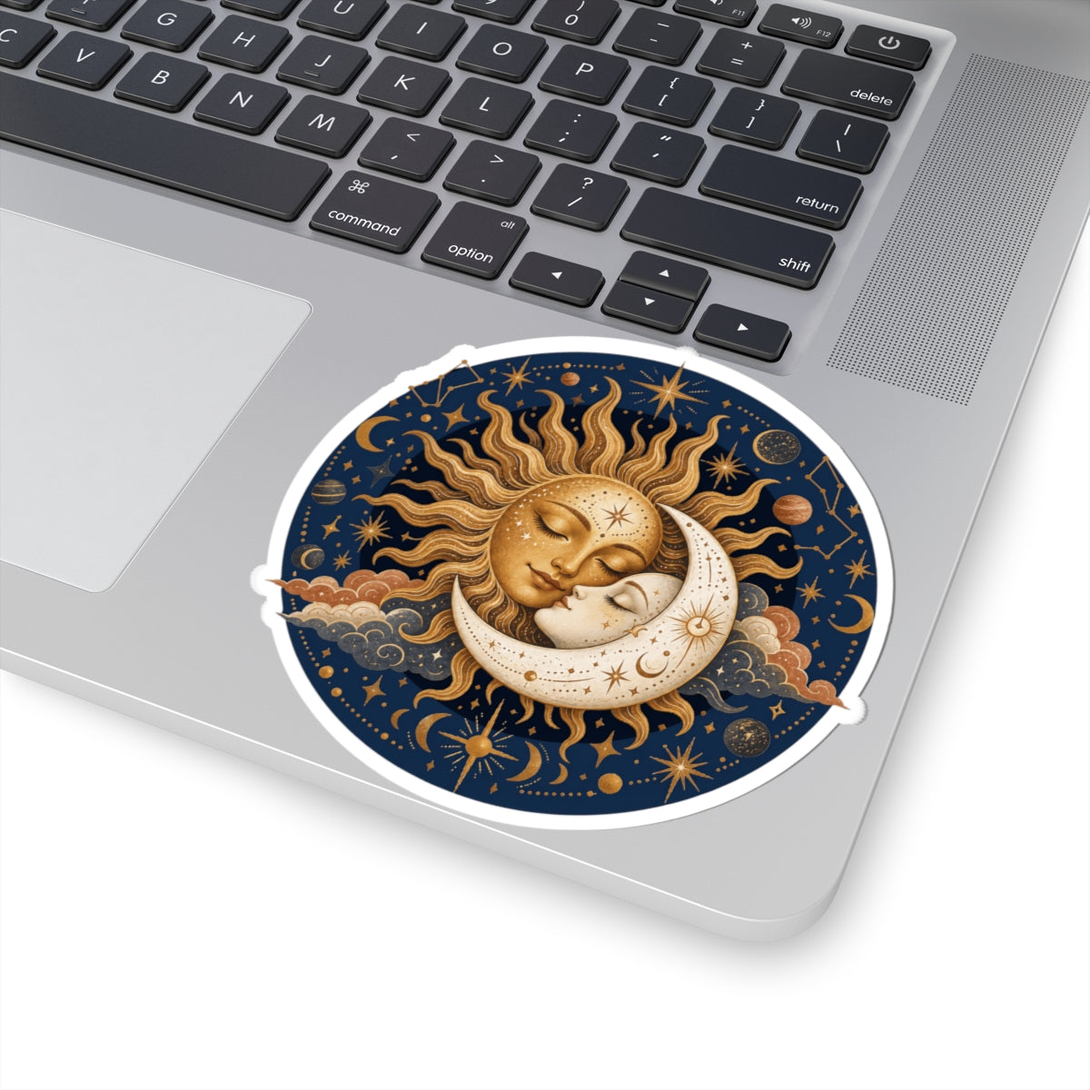 A round sticker with a celestial design of a sleeping sun and moon, applied to the corner of a silver laptop.
