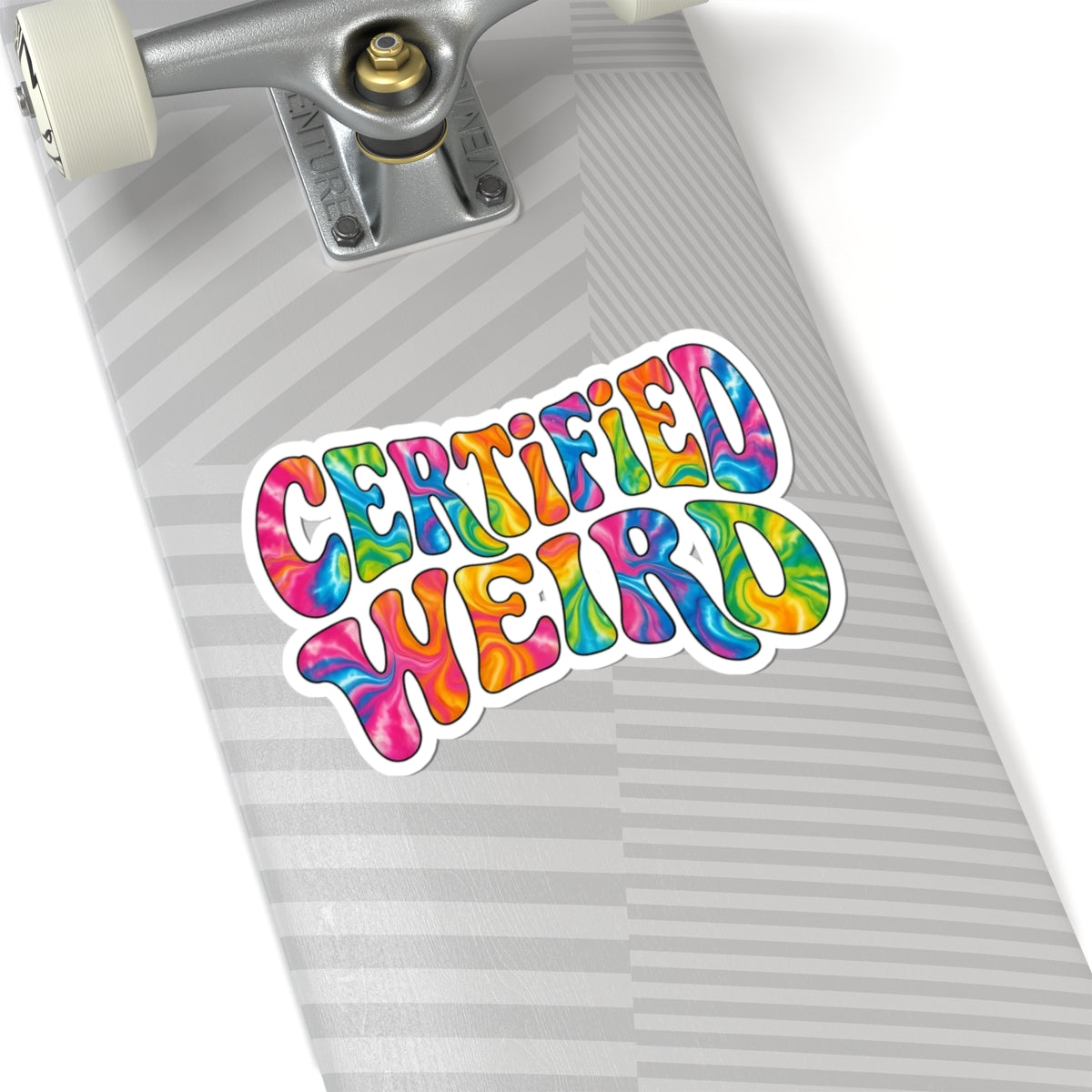 A colorful kiss-cut sticker reading 'CERTIFIED WEIRD' in a rainbow tie-dye pattern, shown on the deck of a skateboard with a silver trucks and white wheels against a white background.