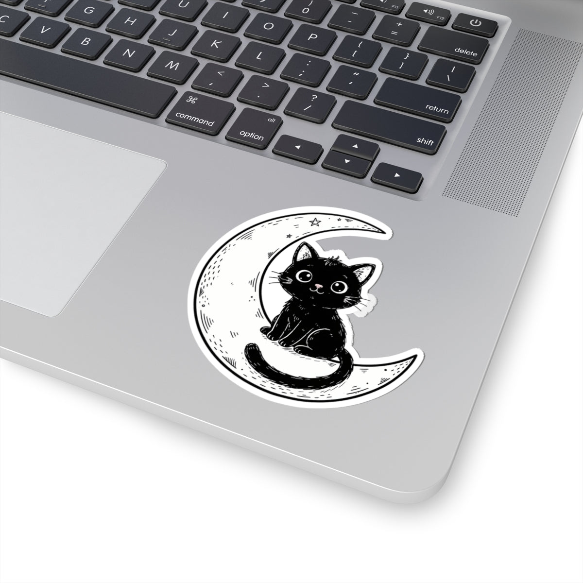 Laptop with a black and white sticker of a cat sitting on a crescent moon on the palm rest area.