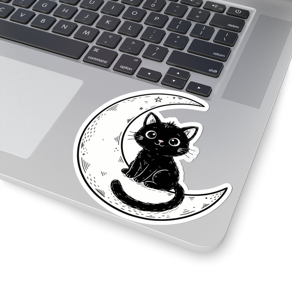 A kiss-cut vinyl sticker of a cute black cat sitting on a crescent moon, shown applied to the corner of a silver laptop.