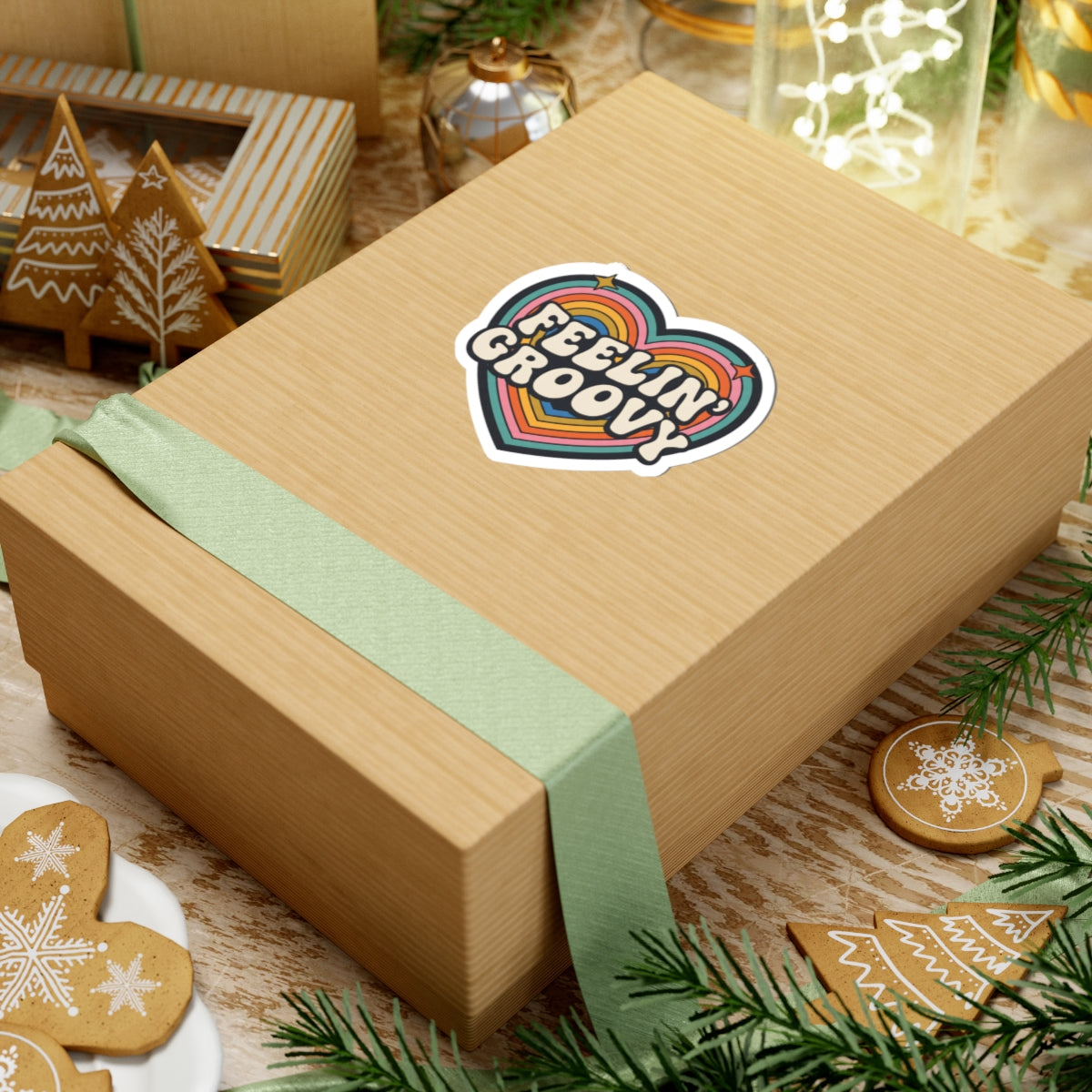 Wooden gift box with a colorful rainbow heart sticker with the text 'FEELIN' GROOVY' on a festive background with cookies and lights.