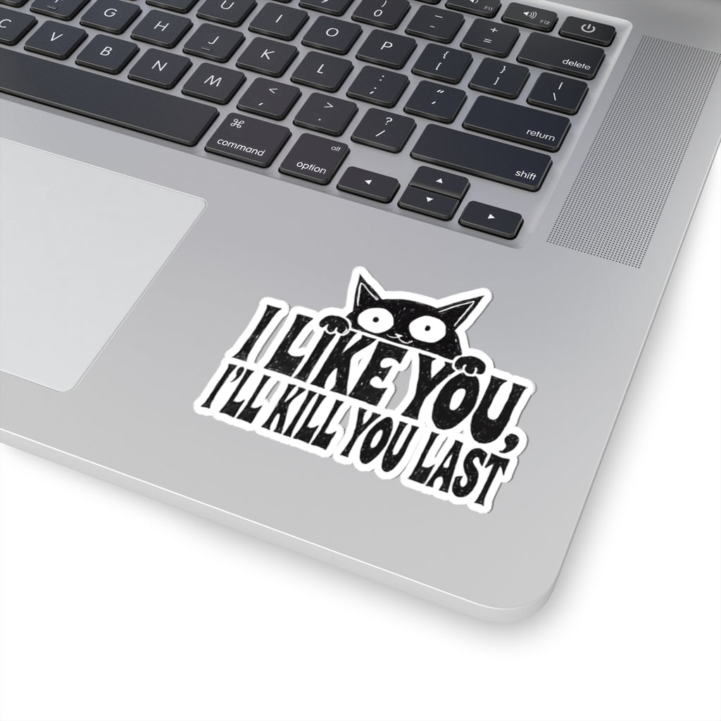 A kiss-cut vinyl sticker with a black cat peeking over the text 'I LIKE YOU, I'LL KILL YOU LAST' in bold black letters with a white outline, shown applied to the palm rest of a silver laptop.