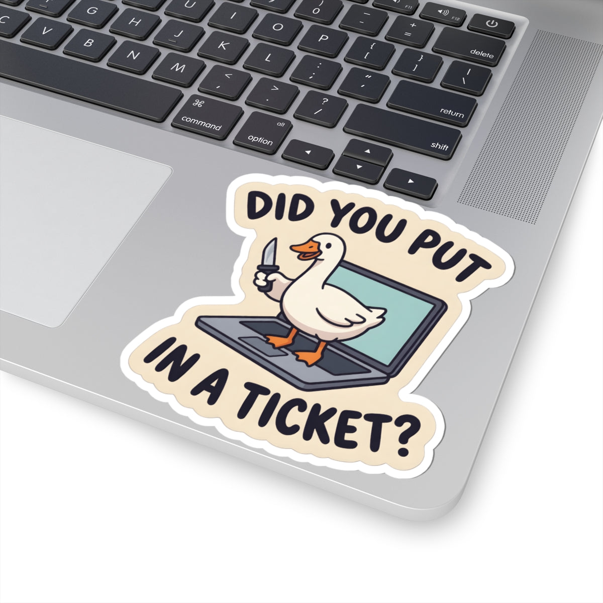 A kiss-cut vinyl sticker featuring a cartoon duck standing on a laptop and holding a knife, with the text 'DID YOU PUT IN A TICKET?' in black letters. The sticker is shown applied to the corner of a silver laptop.