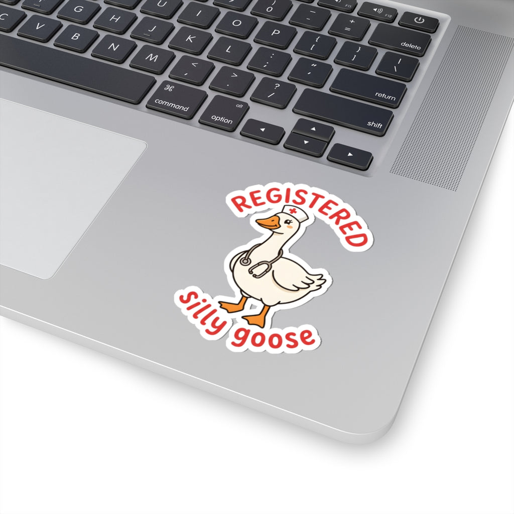 A kiss-cut vinyl sticker featuring a cartoon white goose with an orange beak and legs, wearing a stethoscope, with the words 'REGISTERED SILLY GOOSE' in red. The sticker is shown applied to the silver palm rest of a laptop keyboard.