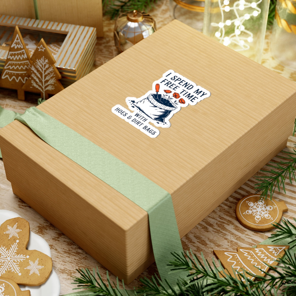 Wooden gift box with a funny garden-themed sticker on a festive background with cookies and greenery.