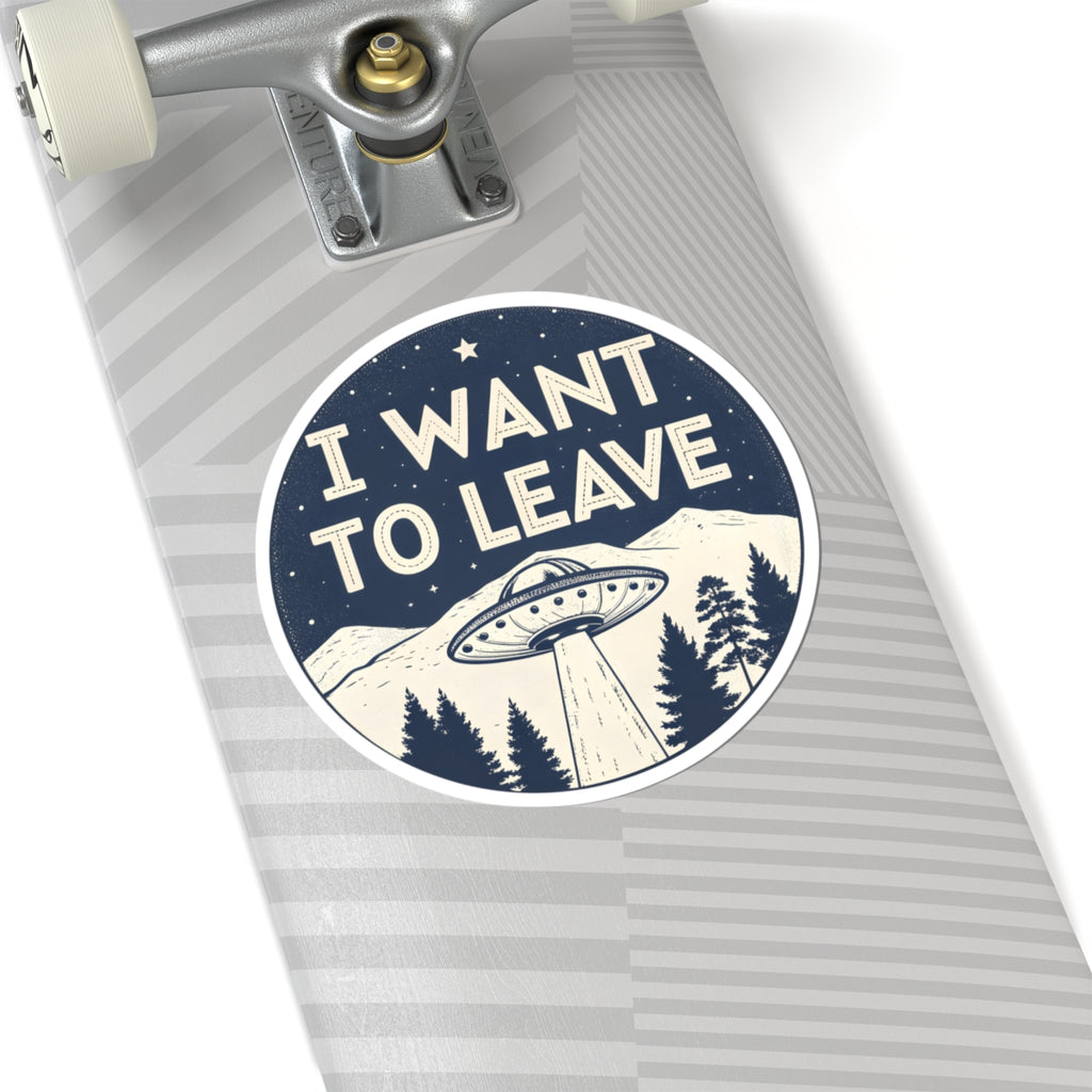 A circular sticker with the text 'I WANT TO LEAVE' and a UFO graphic, shown on the deck of a skateboard with gray striped grip tape.