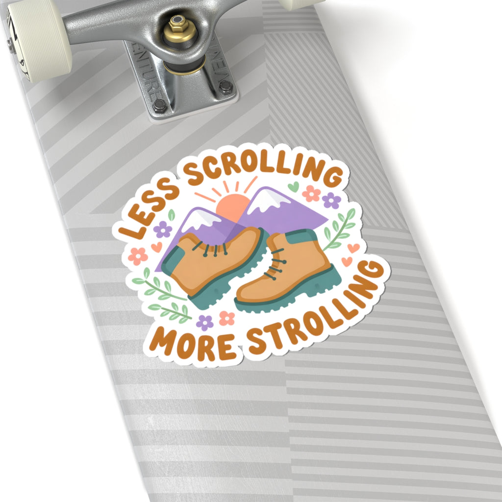A kiss-cut sticker featuring a pair of hiking boots, mountains, and the text 'LESS SCROLLING MORE STROLLING' in orange, displayed on a gray striped skateboard deck.