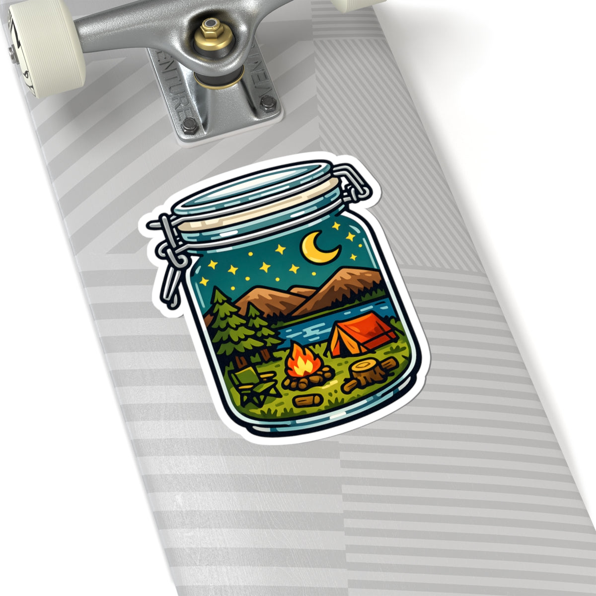 A kiss-cut sticker depicting a camping scene inside a glass jar, shown applied to the side of a silver skateboard deck.