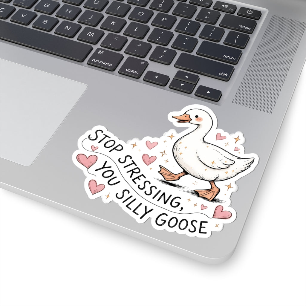 A die-cut vinyl sticker featuring a white cartoon goose with pink hearts and the text 'STOP STRESSING, YOU SILLY GOOSE.' applied to the corner of a silver laptop keyboard.
