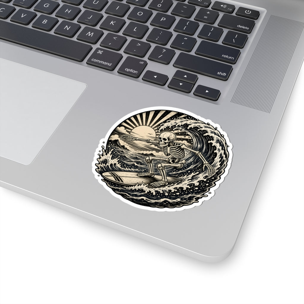 A kiss-cut vinyl sticker featuring a detailed black and white illustration of a skeleton riding a wave, shown applied to the palm rest of a silver laptop.