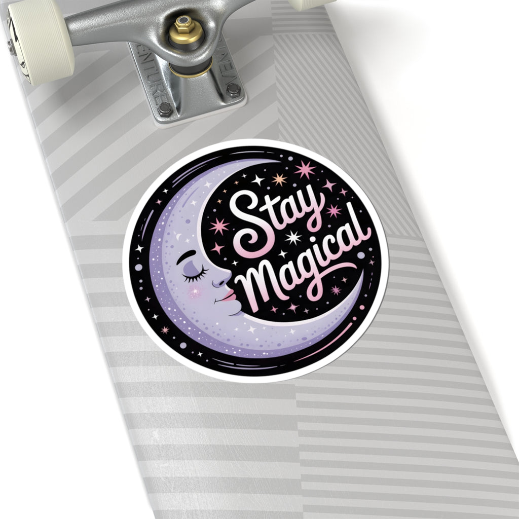 A circular sticker on a gray striped skateboard deck featuring a sleeping moon character and the words 'Stay Magical' in pink and white script.