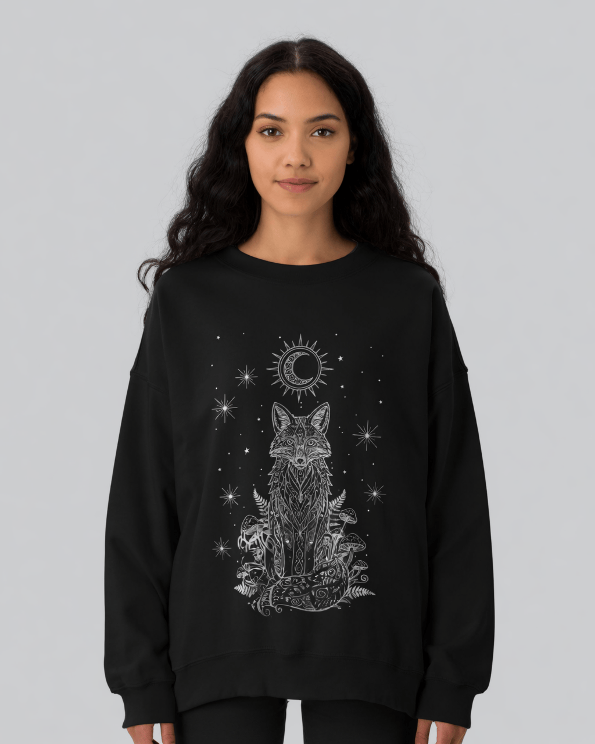 Model with long wavy hair wearing a black Fox Celestial Moon Sweatshirt, featuring an intricate white line-art design of a mystical fox under a crescent moon and stars.