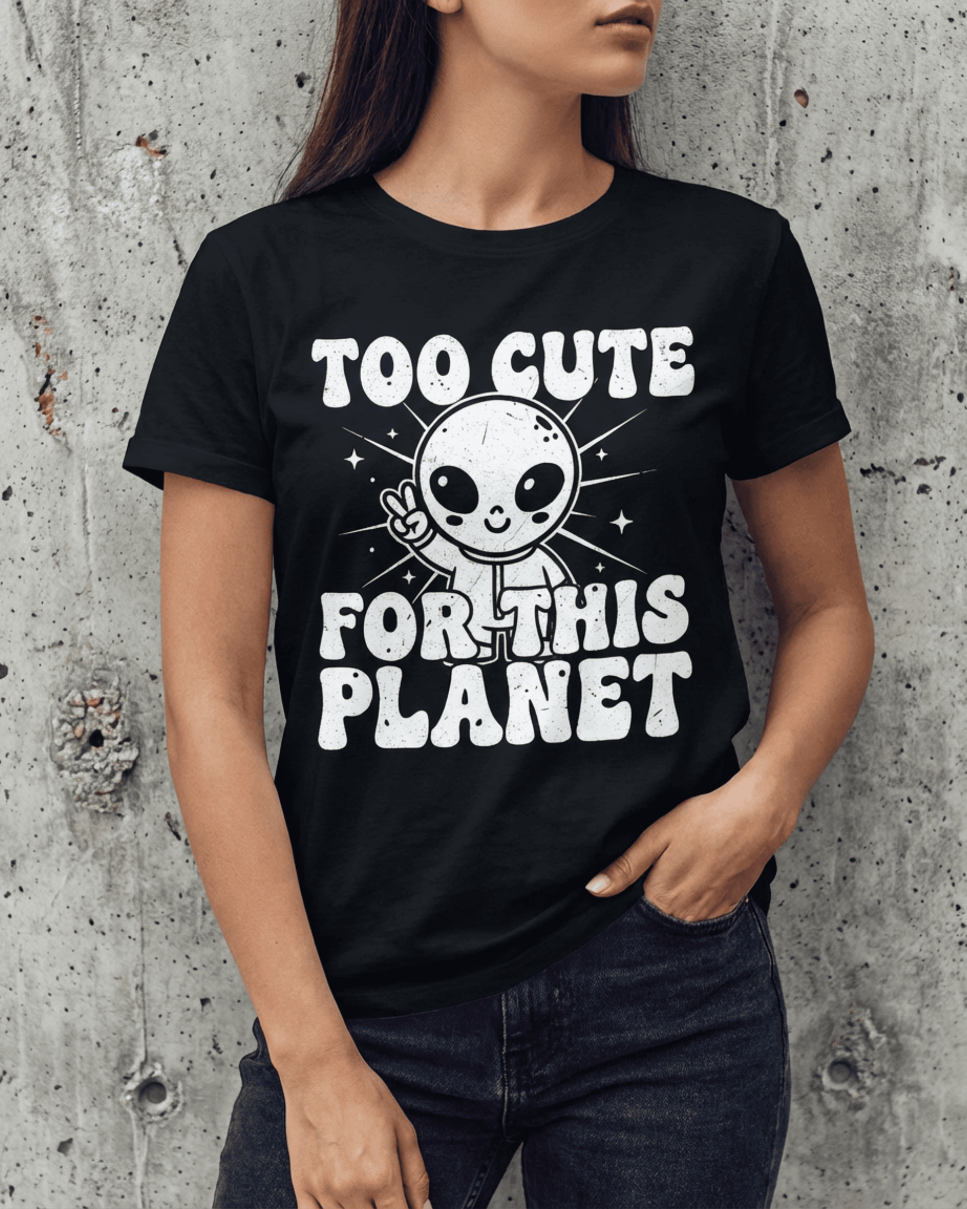 A close-up of a woman wearing the black "Too Cute For This Planet" t-shirt. The funny graphic tee features a cute alien giving a peace sign, printed in a distinct retro 90s style font.