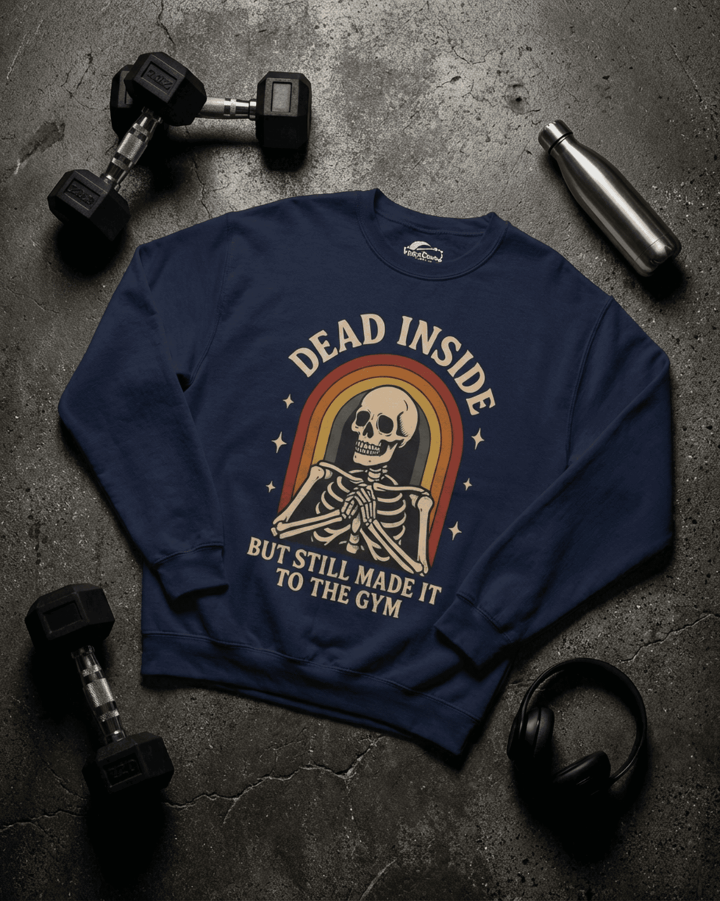 A flat lay of the navy Funny Retro Gym Sweatshirt on a dark concrete floor. The Rainbow Skeleton Dead Inside Pullover is surrounded by dumbbells, headphones, and a water bottle, showcasing its perfect workout and gym-day theme.