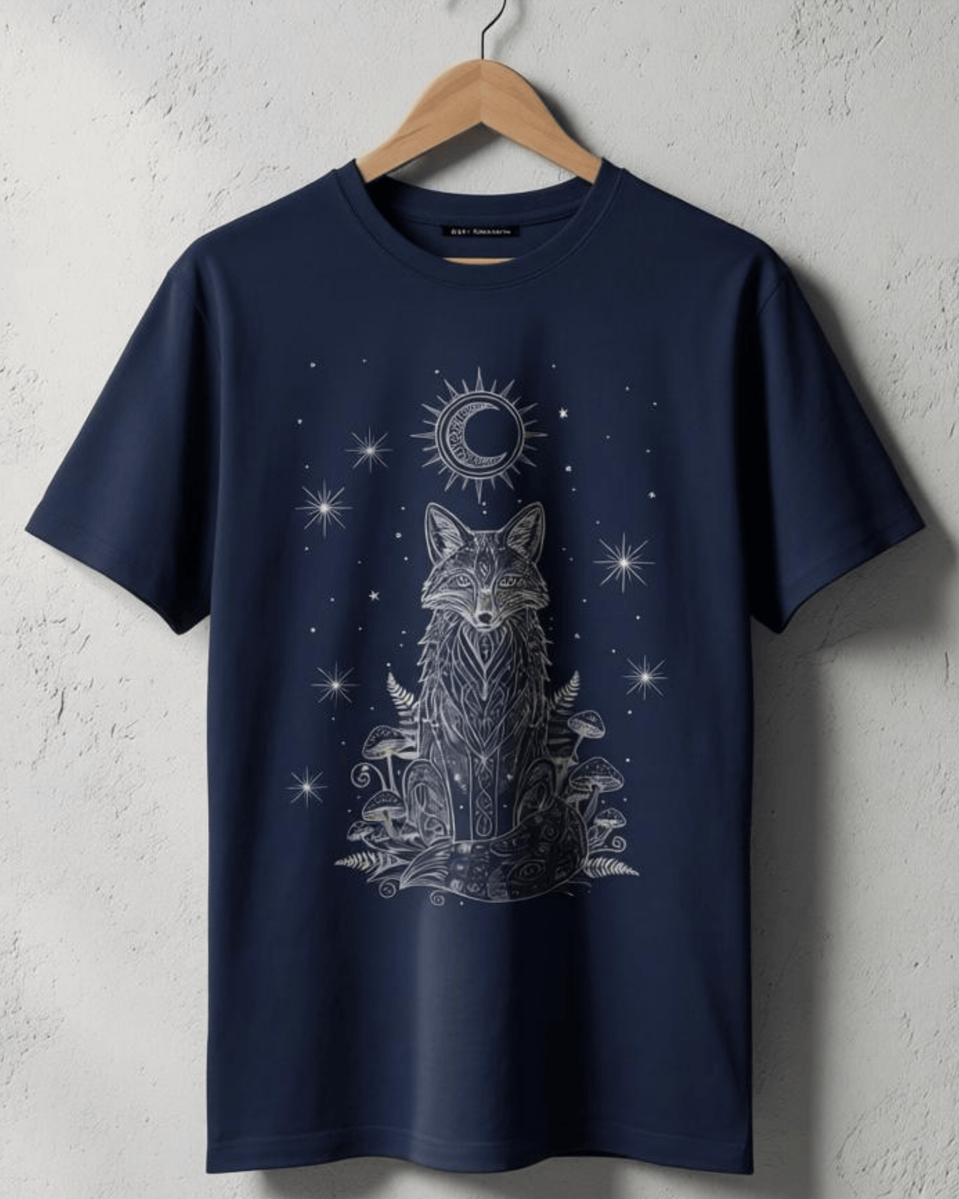 A Navy Fox Shirt hanging on a wooden hanger against a white textured wall. The full front view of the T-Shirt displays the detailed white print of a fox with mandala patterns, mushrooms, and a moon, highlighting the Woodland Top aesthetic.