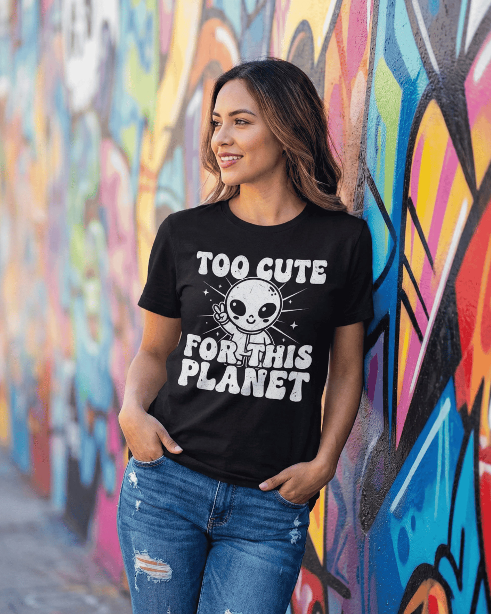 A smiling woman models a black UFO sci-fi shirt while leaning against a colorful graffiti wall. This outer space lover t-shirt for women shows off its trendy, retro Y2K style in a vibrant, urban setting.