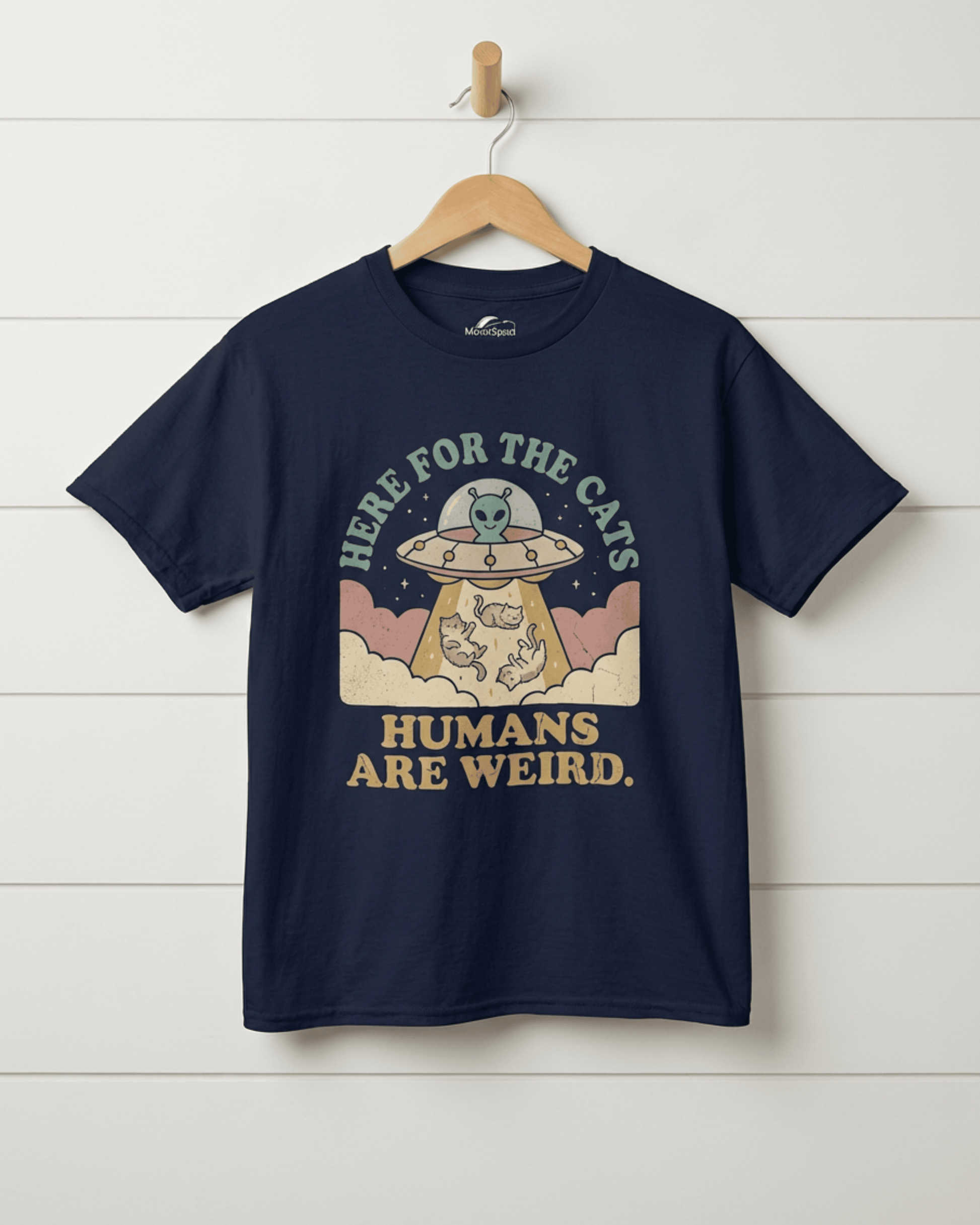 Front view of the navy blue "UFO Here for the Cats" t-shirt on a hanger. This funny kids graphic tee features a friendly alien in a flying saucer because "Humans Are Weird."